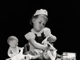 Girl Wearing Nurse's Cap  Putting Bandages on Doll's Head