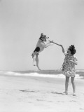 Wire Haired Terrier Dog Jumping in the Air To Catch a Stick Held By Little Girl