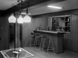 Rec Room Interior With Three Seat Bar  Glass-Topped Table and Wicker Light Fixture