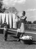 Mother and Daughter Doing Laundry  Hanging Wash on Clothesline in Backyard