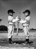 Two Boys in Little League Uniforms  Facing Each Other  Holding Baseball Bat