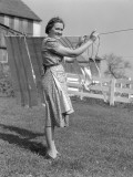 Woman in Apron Smiling As She is Hanging Laundry on Clothesline