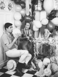 Couple Blowing Up Balloons in Kitchen For Party
