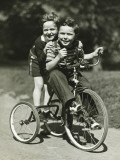 Two Young Boys (6-7) Riding Tricycle in Park  Portrait