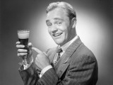 Man in Suit Pointing To Glass of Beer