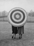 Two Women Holding Up Archery Target in Field