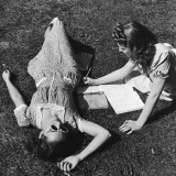 Two Teenage Girls (14-16) on Grass  One Doing Homework