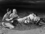 Two Couples on Beach Sitting Around Campfire