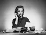 Woman Using Phone and Looking at Paper