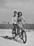 Teenage Boy and Girl Riding Bike Along Beach