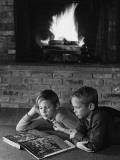 Two Boys Lying on Floor in Front of Fireplace  Reading Book