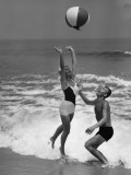 Young Couple Playing With Beach Ball at Water's Edge