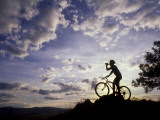 Silhouette of Mountain Biker Drinking at the Summit During Sunset
