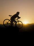 Silhouette of Mountain Biker at the Summit During Sunrise