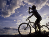 Silhouette of Mountain Biker Drinking at the Summit During Sunset
