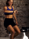 Young Woman Exercising on a Stationary Bike Checking her Heart Rate