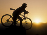 Silhouette of Mountain Biker at the Summit During Sunrise