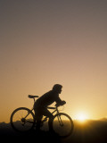 Silhouette of Mountain Biker at the Summit During Sunrise