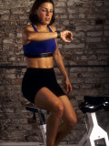 Young Woman Exercising on a Stationary Bike Checking her Heart Rate