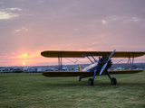 A Stearman Biplane on a Grass Airfield at Dawn