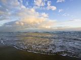 Storm Clouds Reflect Pastel Colors in Waves Rolling into Shore