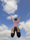Young Woman Jumping  with a Cloud-Filled Sky in Front of Her