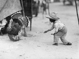 A Young Guatemalan Boy in a Straw Hat Tries to Coax a Turkey to Him