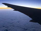 The Wing of an Airplane Above a Thick Layer of Cumulus Clouds at Dawn