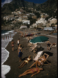 Sunbathers Lounge on a Pebbled Beach by Whitewashed Houses on a Cliff