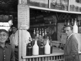 A Man Stands at the Edge of a Bar Surrounded by Bottles