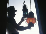 A Man Handles Red and Green Lanterns Hanging Near a Doorway