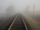 Railroad Tracks Stretch into Thick Fog in Early Morning