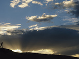A Silhouetted Figure Trail Running under a Cloud Filled Sky