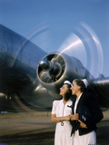 Two Young Women Stand Near a Turning Aircraft Propeller