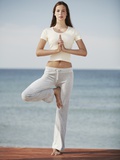 Woman doing yoga by the ocean