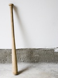 Detail of wooden baseball bat against white and concrete wall