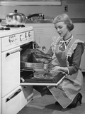 Young woman putting turkey into oven