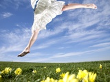 Young woman in park jumping on lawn