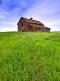 Abandoned red barn sitting on the top of a hill on a pioneer homestead in rural Alberta Canada