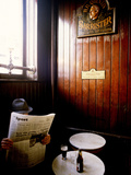A Man with a Beer Reading a Newspaper in a Pub