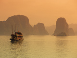 Traditional Boat Sailing Through Limestone Archipelago at Sunset  Ha Long Bay  UNESCO World Heritag