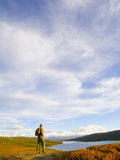 Hiker Looking at Alaska Range and Wonder Lake under a Cloudy Sky