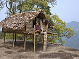 A Man Sits on the Veranda of His Small House  Raised on Stilts  Situated Precariously on the Edge o