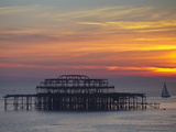 UK  England  Sussex  Brighton  Boat Sailing Past Remains of Brighton West Pier at Sunset