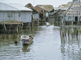 Local Woman Paddling Her Pirogue Through Granville Stilt Village  Benin