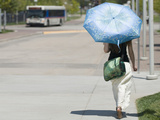 A Woman Wears Loose Fitting Clothing and Carries an Umbrella to Block the Sun During Heat Wave