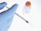Gloved Hand Holding a Syringe with a Bottle of Insulin