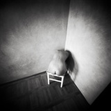 A Naked Female Figure Sitting on a Stool in the Corner of an Empty Room