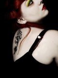 A Dark Portrait of a Girl with Red Hair and a Tattoo on Her Back