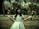 A Young Girl with Long Dark Hair Dressed in White Wearing Gloves Looking at White Butterflies
